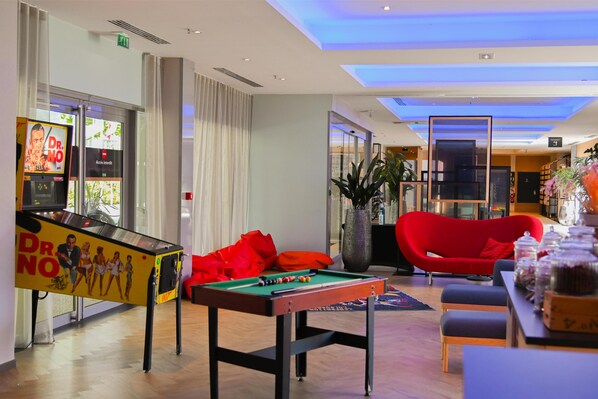 A modern lounge area with a pool table, red seating, and a Dr. No advertisement.