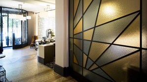 Un interior moderno con pared de diseño geométrico, un mostrador de recepción y una zona de estar.