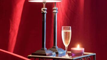 Una mesa con una lámpara, una copa de champán y una vela.