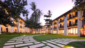 A hotel courtyard with a paved walkway, palm trees, and a building with multiple balconies. - ibis Samui Bophut (Koh Samui)