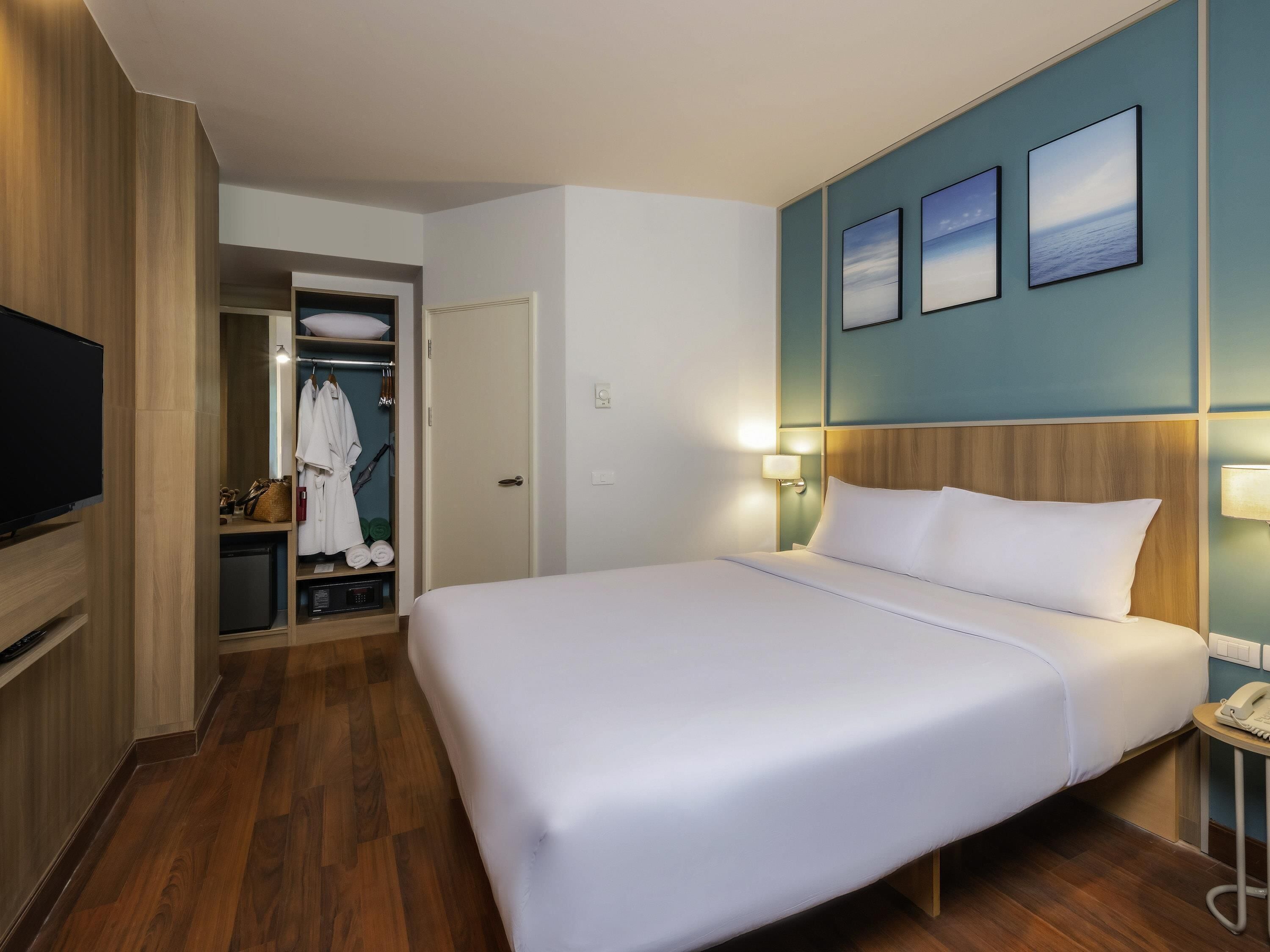 Ein Hotelzimmer mit einem großen Bett, einem Fernseher, einem Kleiderschrank und einem Badezimmer.