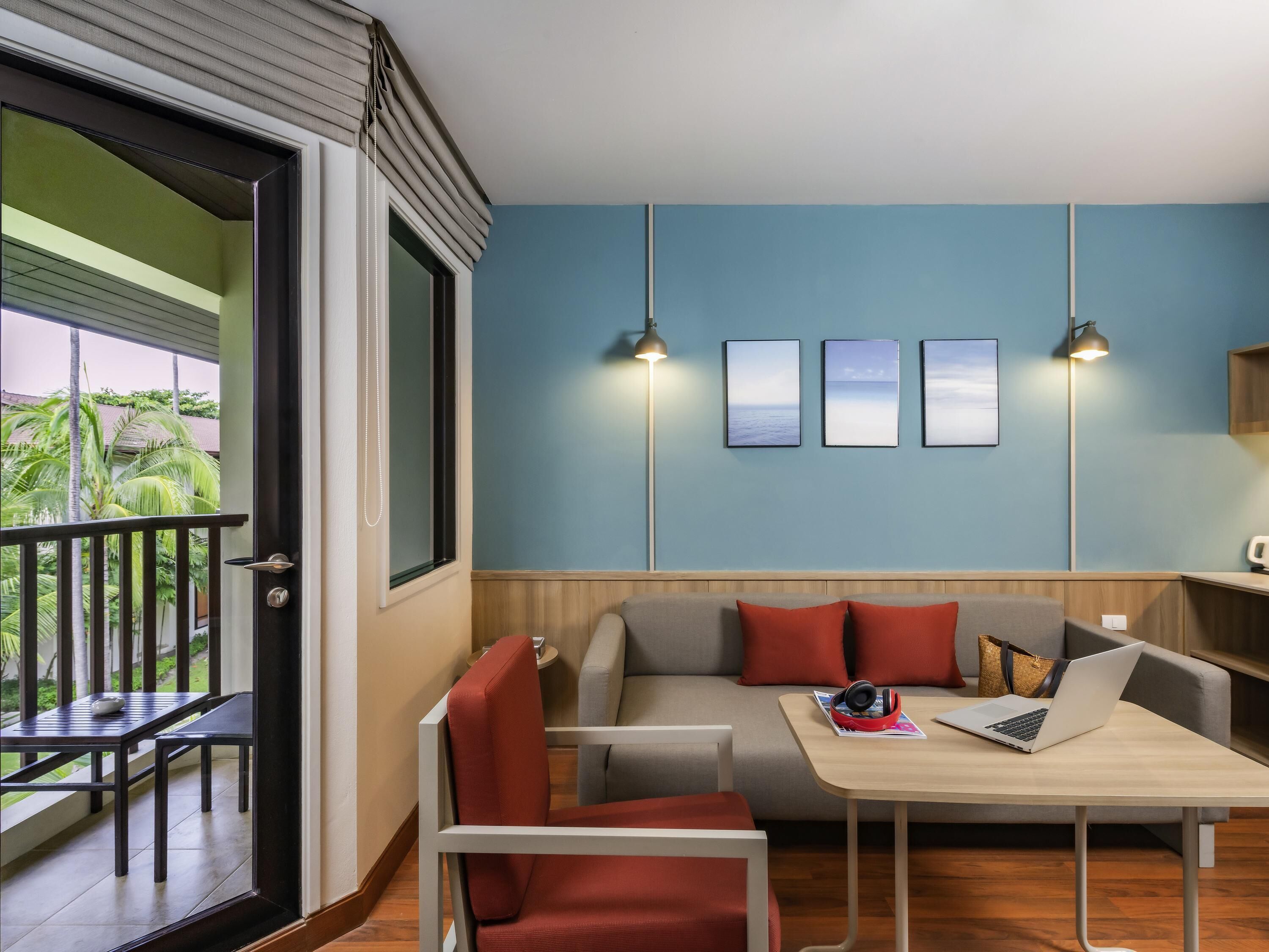 Una habitación moderna con balcón, sofá, mesa y una computadora portátil.