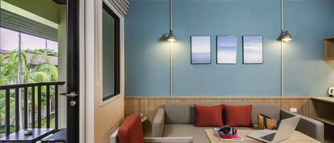 Una habitación moderna con balcón, sofá, mesa y una computadora portátil.