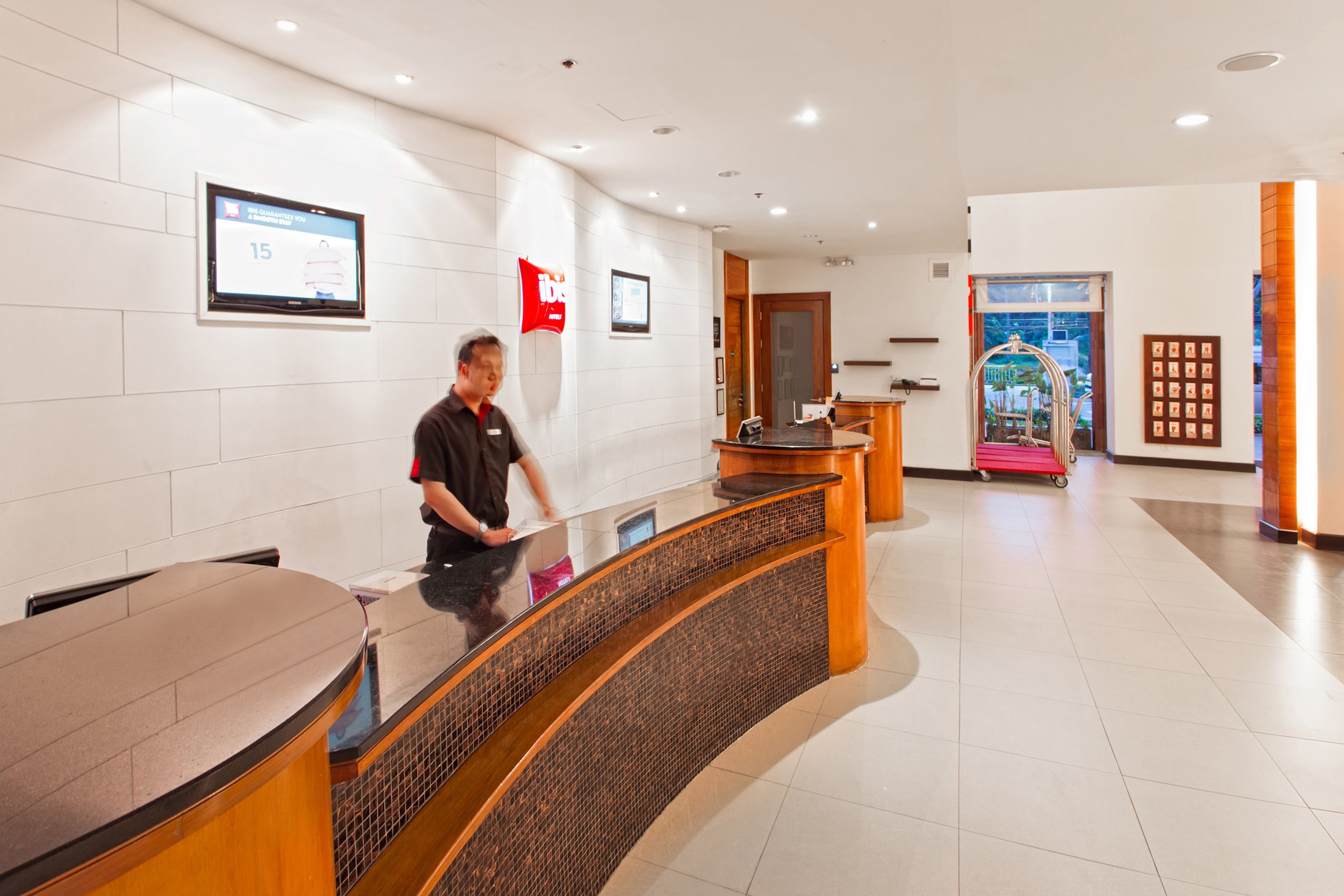 A hotel reception area with a curved reception desk, a digital display, and a red flag on the wall.