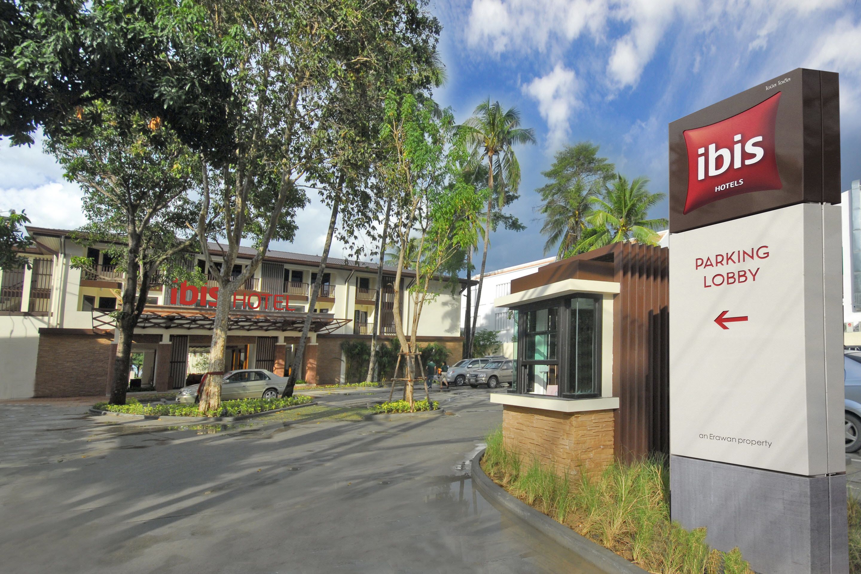 L’entrée d’un hôtel, avec une enseigne indiquant la présence d’hôtels Ibis et un panneau indiquant la direction du parking.