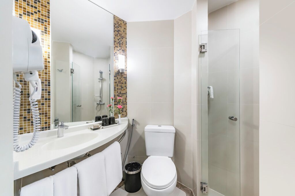 A modern bathroom with a white sink, a toilet, a shower, and a glass-enclosed shower area.
