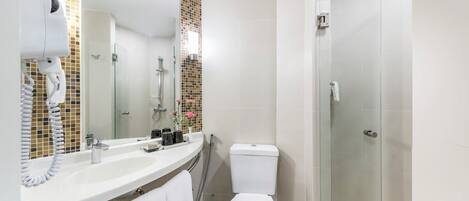 A modern bathroom with a white sink, a toilet, a shower, and a glass-enclosed shower area.