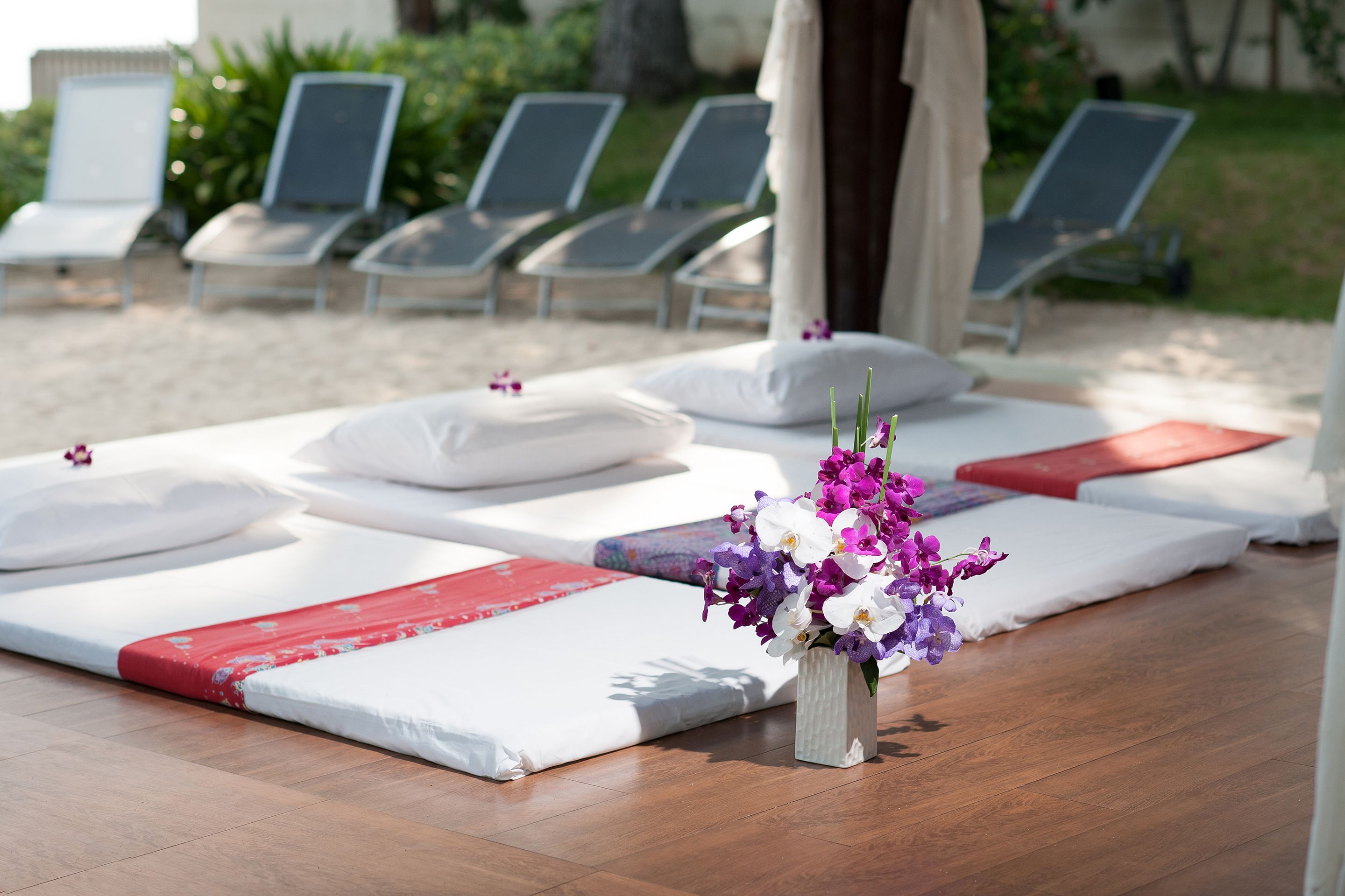 Un espacio de spa con camillas de masaje, un arreglo floral y sillones de descanso.