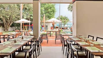 A restaurant with outdoor seating, tables with green placemats, and umbrellas.