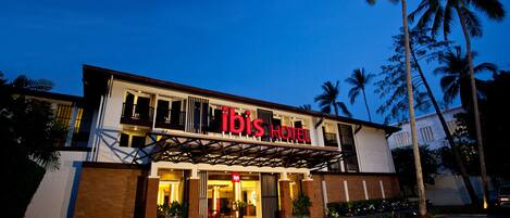 A hotel with a modern facade, a prominent sign, and a well-lit entrance.