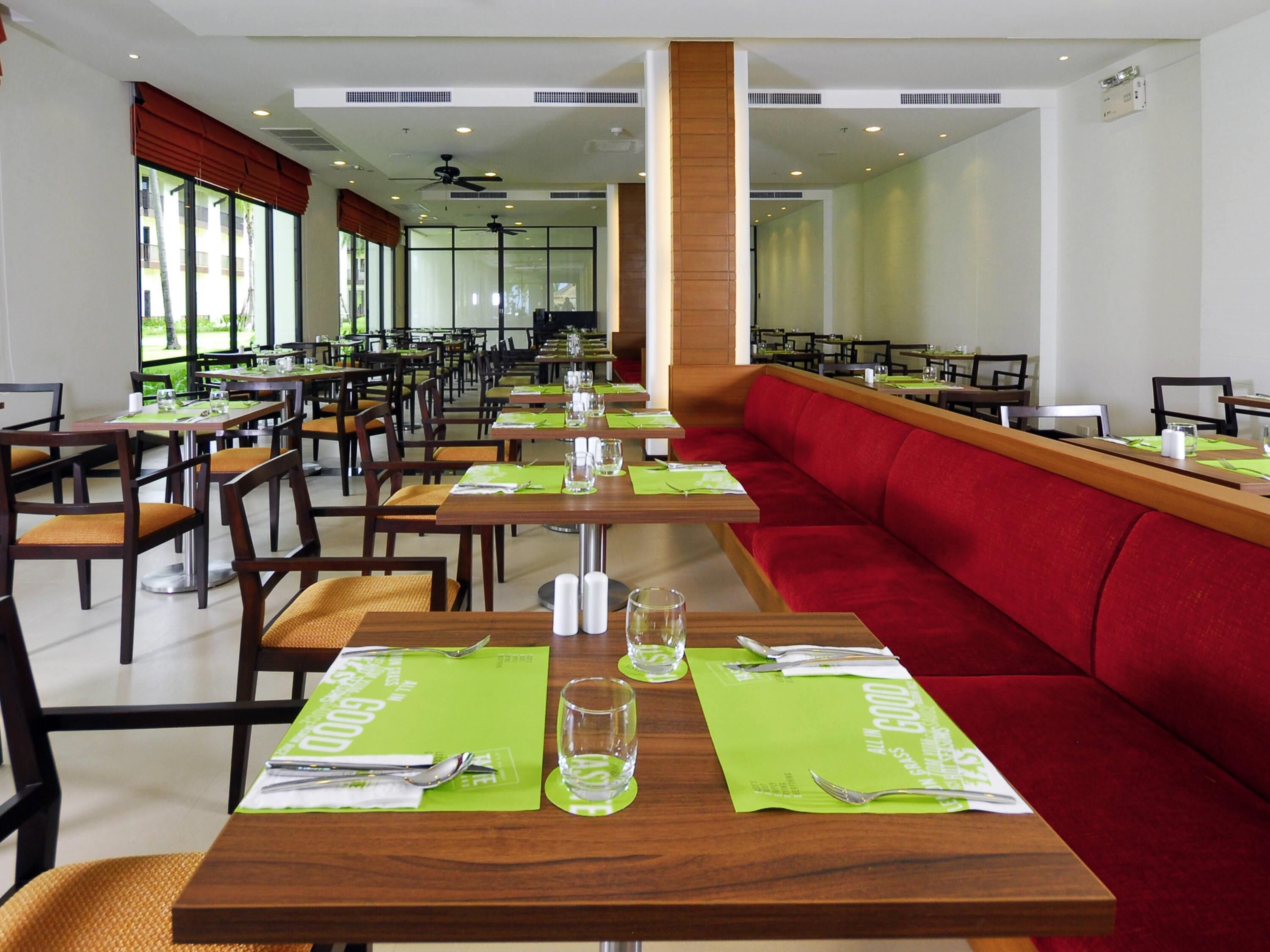 A restaurant with multiple dining tables, chairs, and a red booth area.