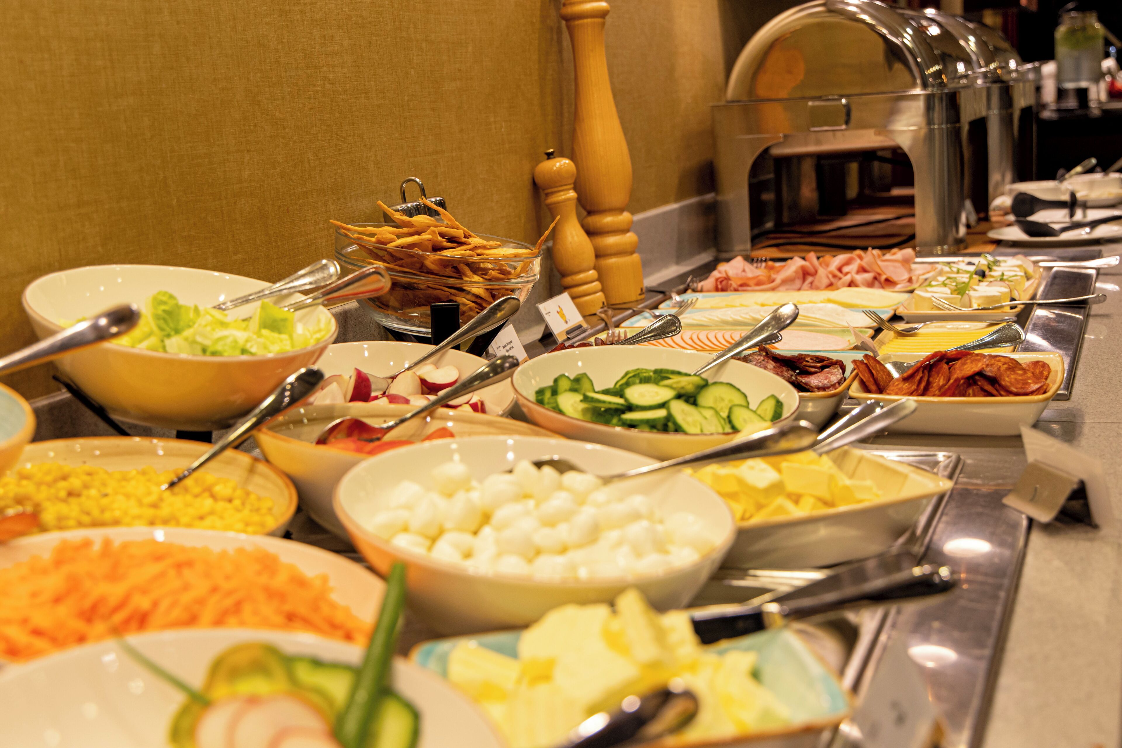 Un buffet proposant une variété de plats, notamment des salades, des fromages et des viandes.