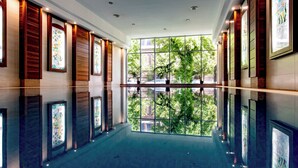 A hallway with large windows, wooden paneling, and framed artwork. - Lions Garden Hotel (Budapest)