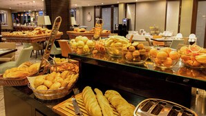 A buffet with various food items including fruits, pastries, and bread. - Lions Garden Hotel (Budapest)