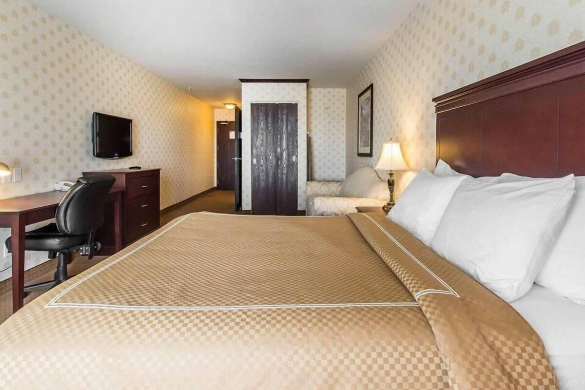 A hotel room with a bed, desk, chair, television, and a door leading to another room.