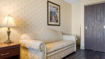 A room with a patterned wallpaper, a framed picture on the wall, a dark wooden door, and a beige sofa.