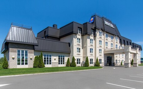 A modern hotel with a prominent sign, multiple floors, and a parking lot.