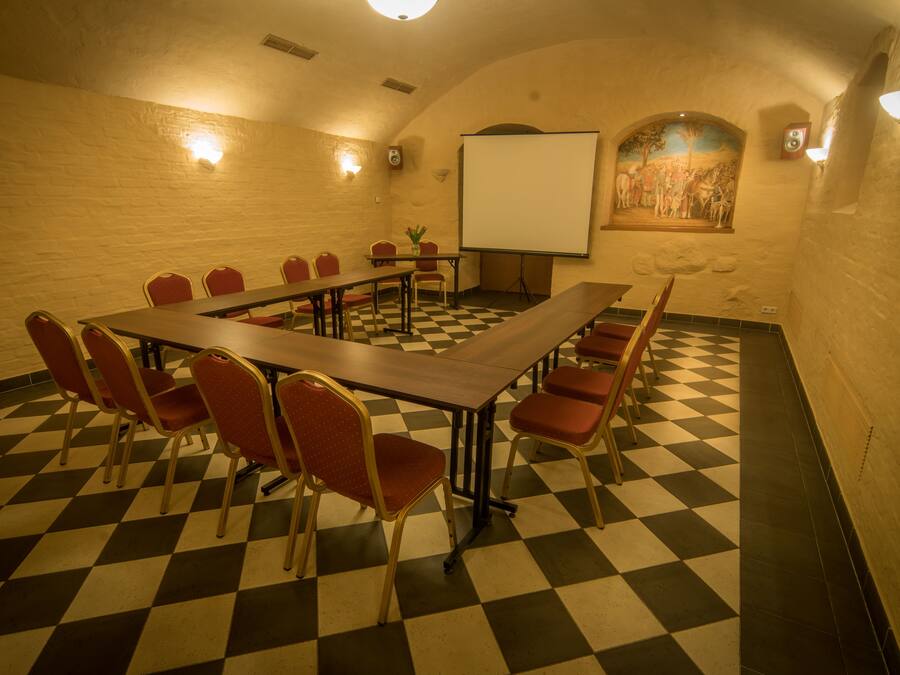 A conference room with a checkered floor, a long table, and red chairs.