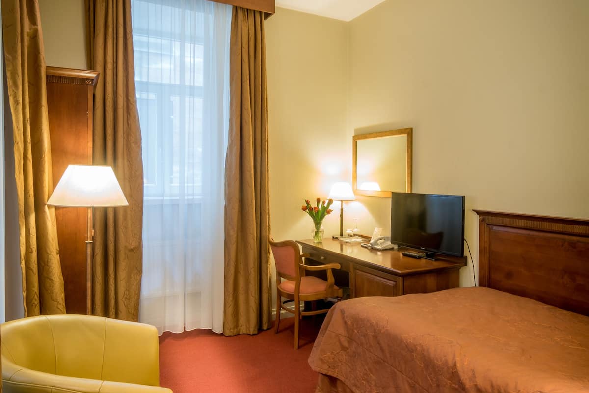 Ein Hotelzimmer mit Bett, Schreibtisch mit Lampe, Stuhl und Fernseher.