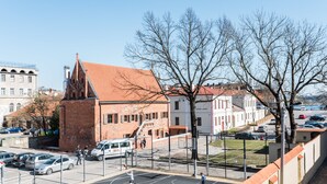 A basketball court with a net, surrounded by buildings and parked cars. - Daugirdas Hotel (Kaunas)