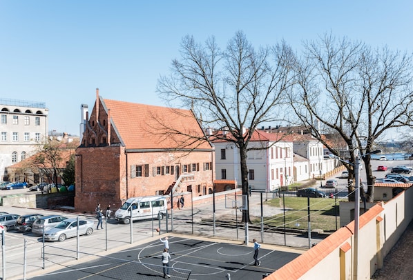 A basketball court with a net, surrounded by buildings and parked cars. - Daugirdas Hotel (Kaunas)