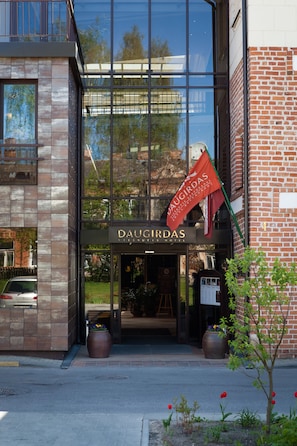 A hotel entrance with a glass facade, a brick wall, and a flag. - Daugirdas Hotel (Kaunas)