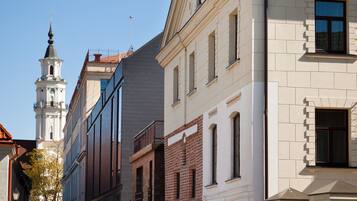 Calle con edificios históricos, una torre del reloj y cielo azul despejado.