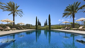 A clear swimming pool with lounge chairs and umbrellas, surrounded by palm trees and cypress trees. - Torrent Fals Agroturismo (Santa Maria del Camí)