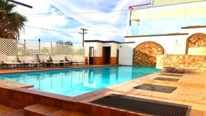 A swimming pool with lounge chairs and a stone wall.