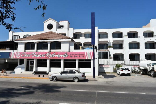 A building with a restaurant named "Cinco Sabores Restaurante" and a parking area. - Costa Ensenada (Ensenada)