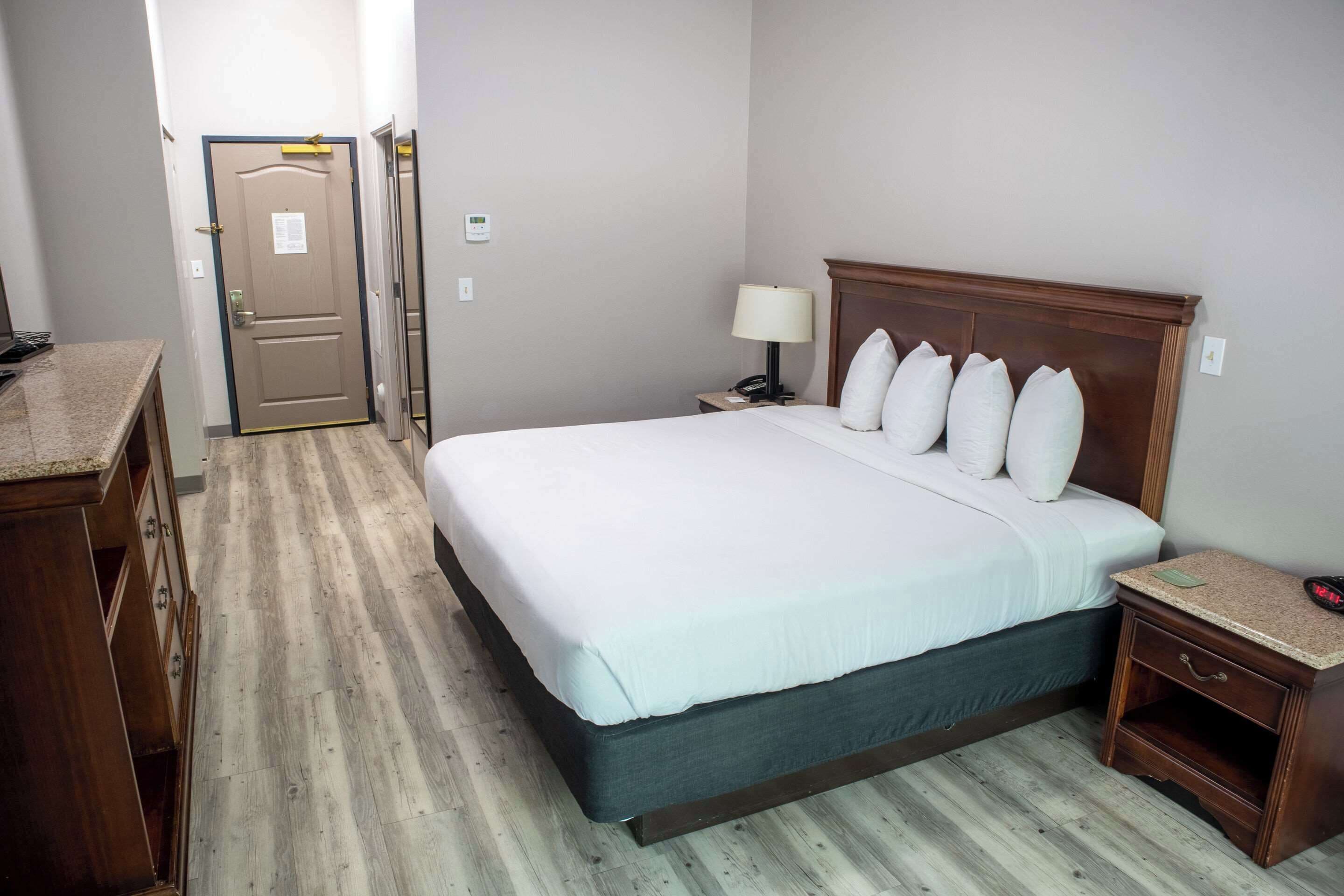 Ein Hotelzimmer mit Bett, Nachttisch, Lampe und einem Holzschrank.