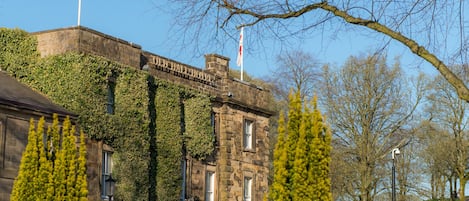 A historic stone building with ivy-covered walls and a flagpole.