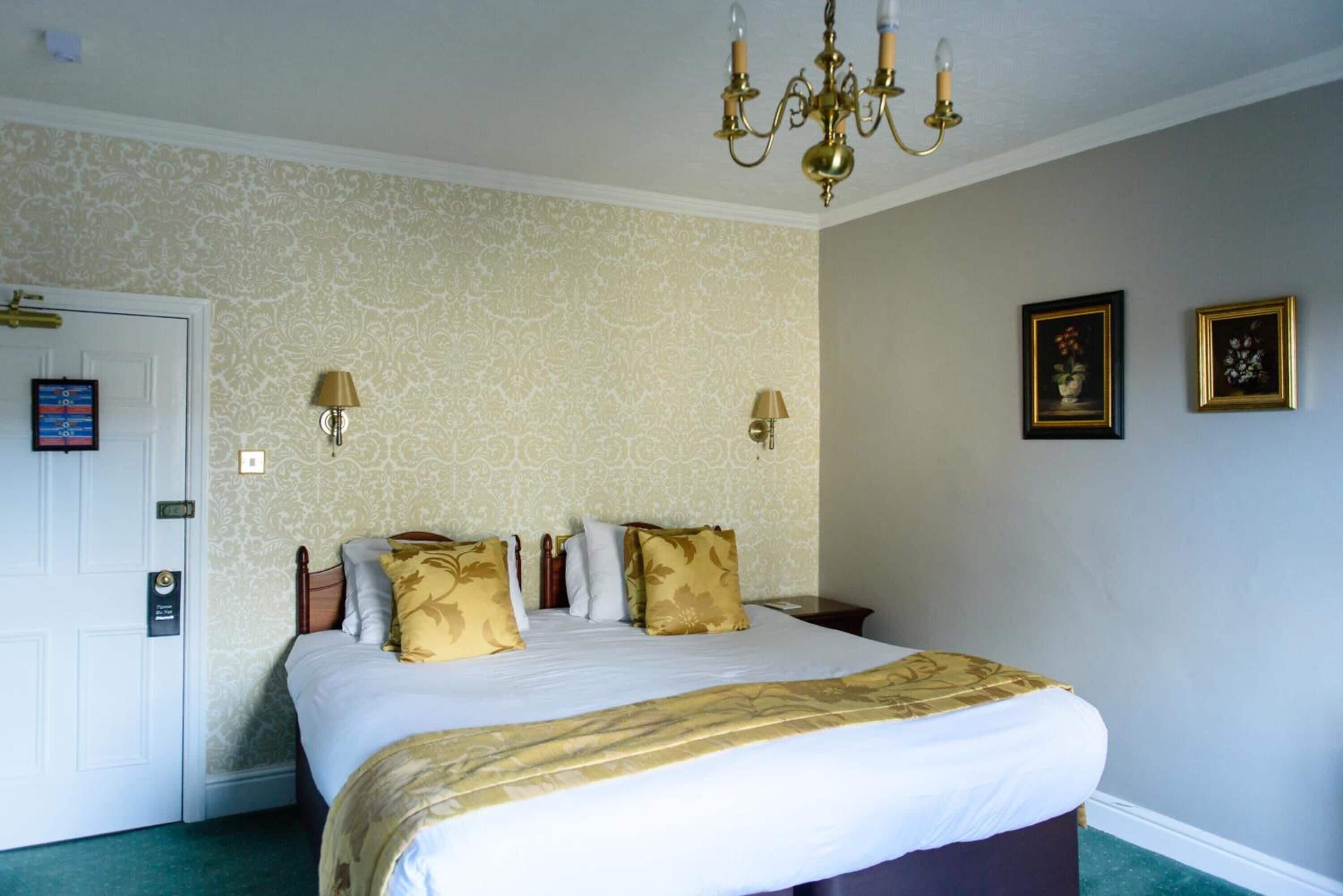 Ein Hotelzimmer mit einem großen Bett, zwei Wandlampen und einem Kronleuchter.