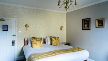 Habitación de hotel con una cama grande, dos lámparas de pared y una araña.
