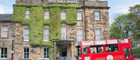 Un edificio histórico con muros cubiertos de hiedra y un letrero que dice 'Old Hall Hotel'.