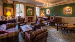 A traditional room with plaid furniture, a fireplace, and framed artwork on the walls. - Old Hall Hotel (Buxton)