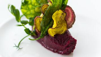 Un plato con base de remolacha, hojas amarillas y verdes, y una ramita de verdura.