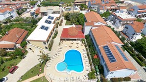 An aerial view of a residential area with a swimming pool surrounded by lounge chairs and a small garden. - Konstantina Apartments (Corfu)