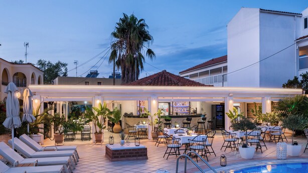 A rooftop bar with outdoor seating, a pool, and palm trees. - Konstantina Apartments (Corfu)