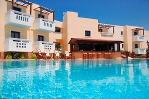 Ein Hotel mit Schwimmbad, einer Poolbar und mehreren Balkonen.