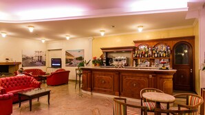 Una zona de bar con mostrador de madera, asientos tapizados en rojo y un televisor al fondo.