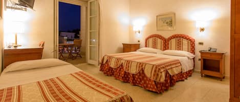 A hotel room with two beds, a television, a desk with a lamp, and a view of the outside.