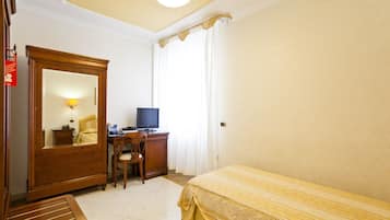Ein Schlafzimmer mit einem Bett, einem Schreibtisch mit Computer, einem Stuhl, einem Kleiderschrank und einem Spiegel.