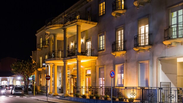 Un hotel de varios pisos con una entrada imponente, columnas y balcones.