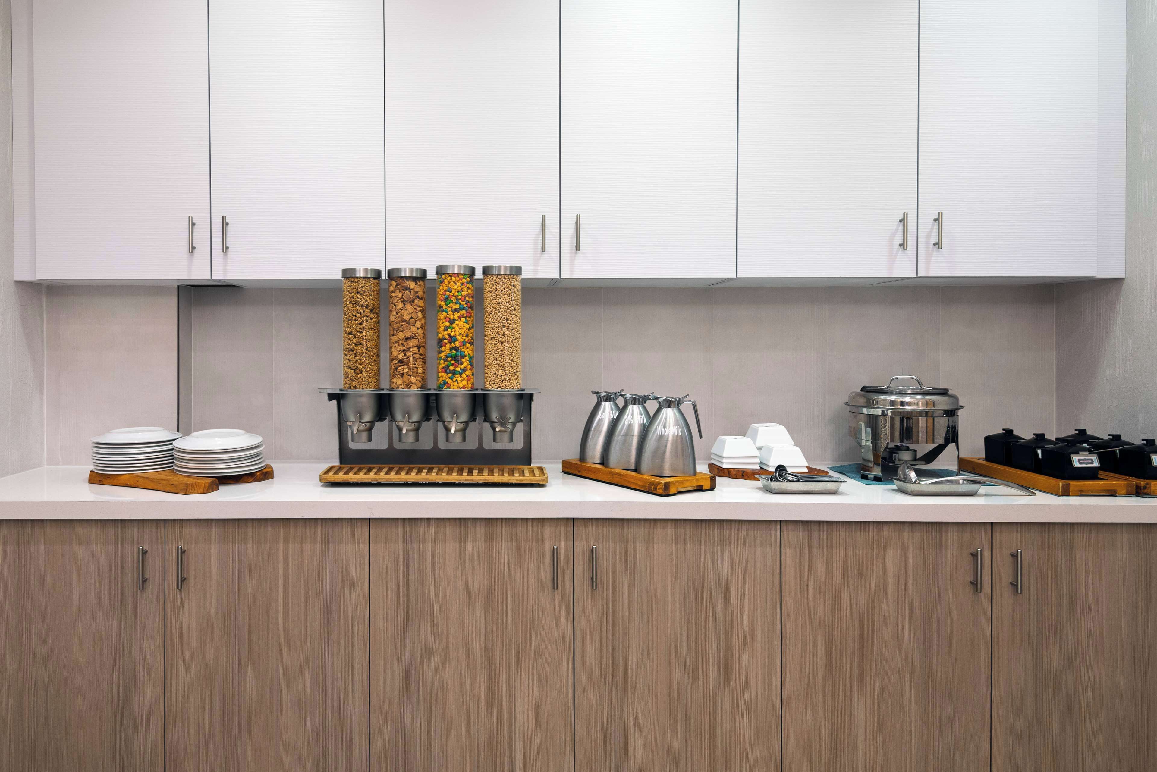 A kitchen with white cabinets, a coffee station, and a coffee maker.