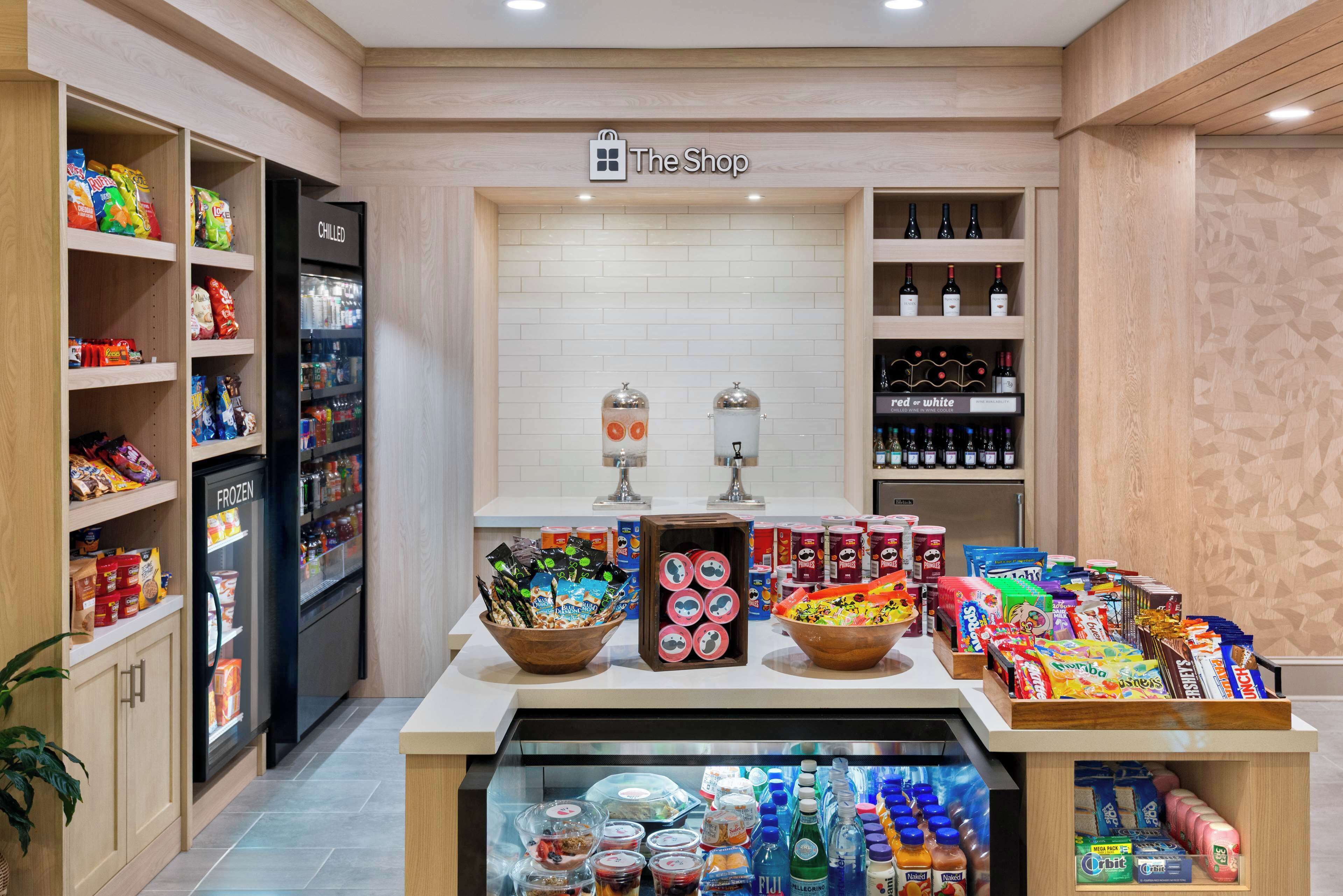 Un magasin dont les étagères sont remplies d’en-cas, avec un rayon réfrigéré et un présentoir de boissons en bouteille.