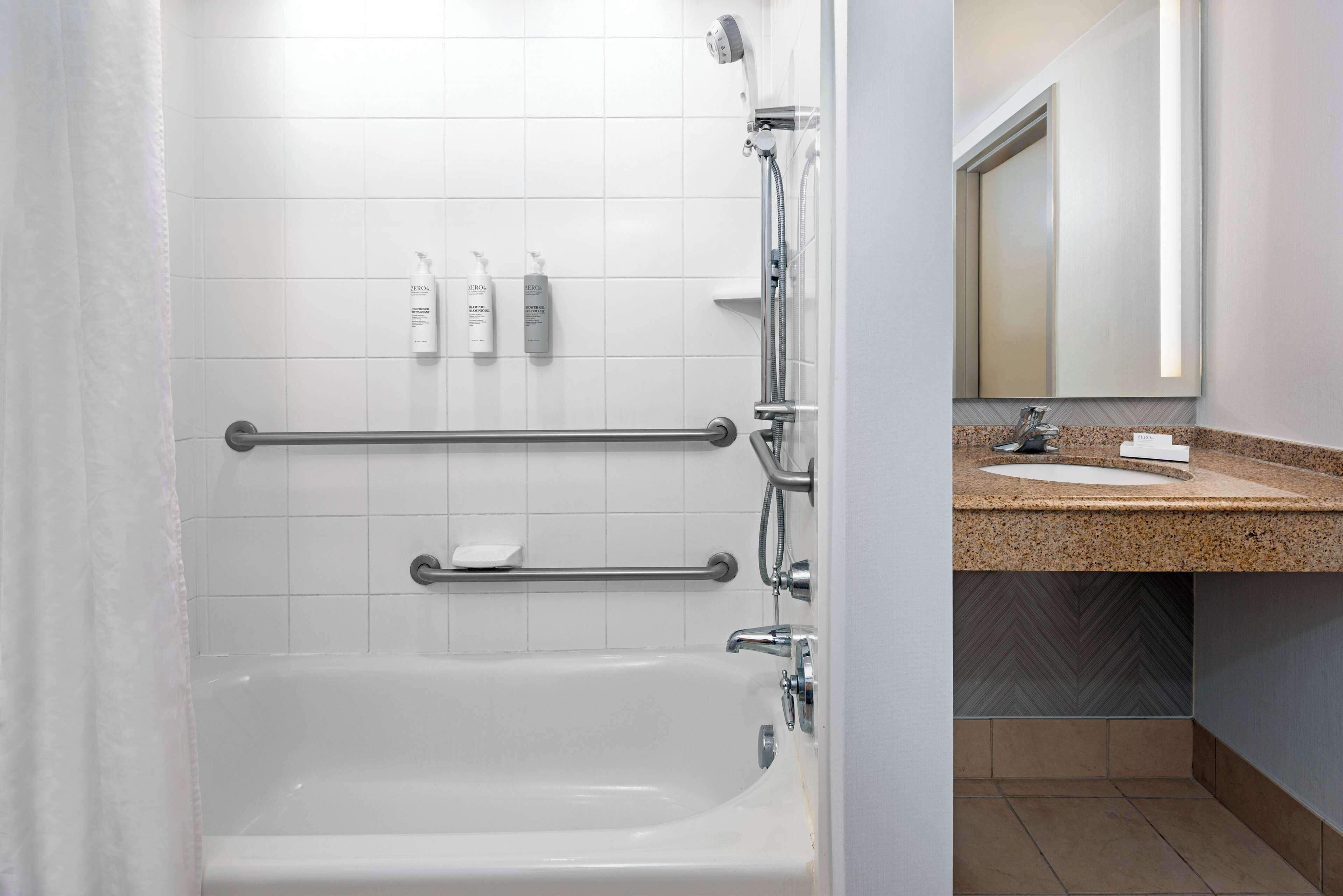 Une salle de bain avec une baignoire blanche, une douche et un meuble-lavabo avec un miroir.