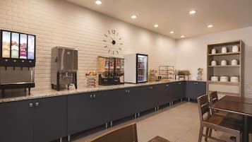Una cocina moderna con un reloj, una cafetera, un refrigerador y una zona tipo bufé.