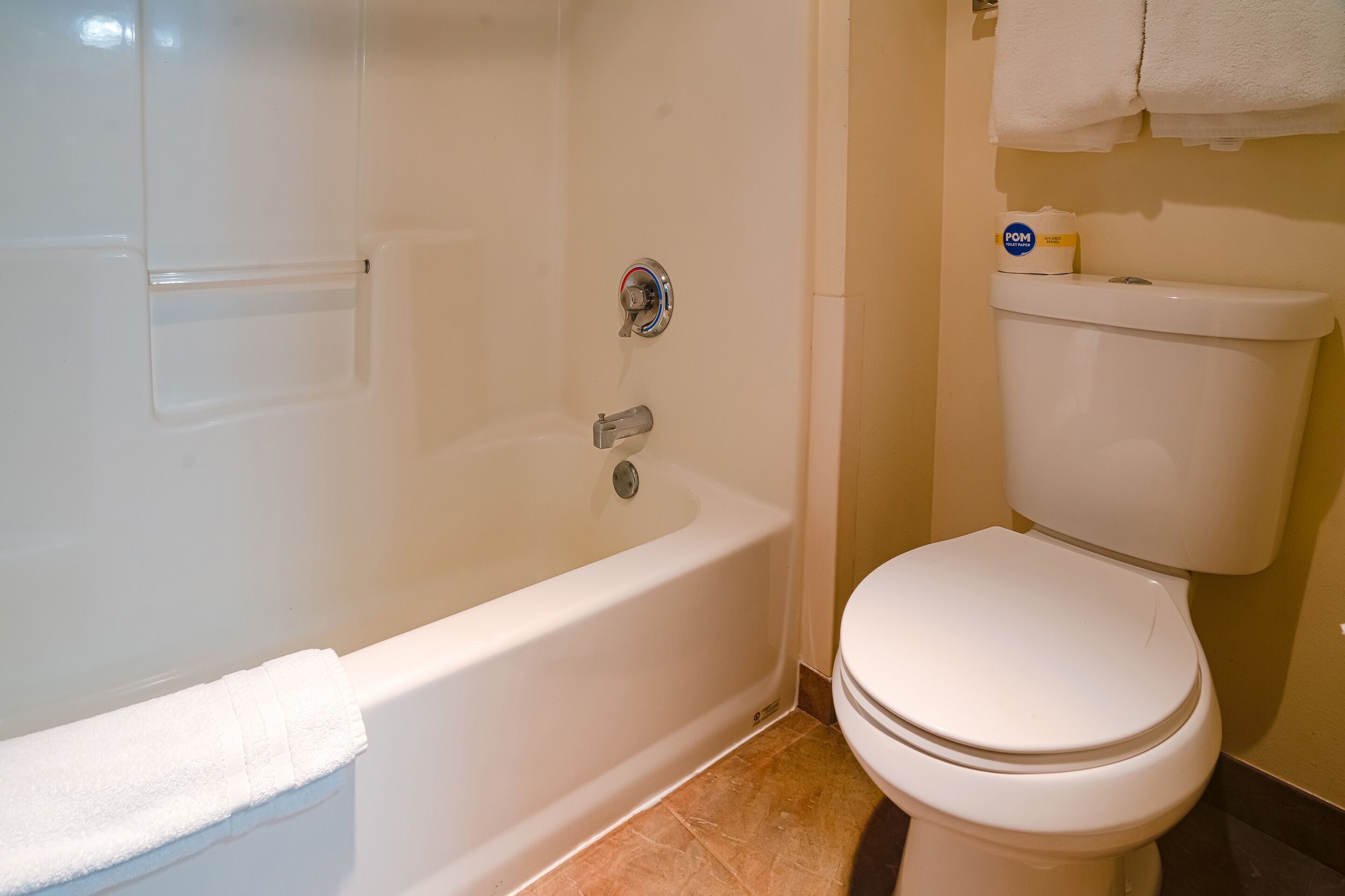 A bathroom with a bathtub, toilet, and a towel rack.