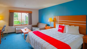 A hotel room with a large bed, a desk, a chair, and a window with curtains. - OYO Hotel Redwood Falls near Jackpot Casino (Redwood Falls)